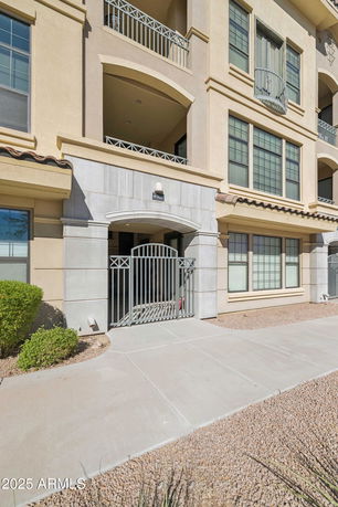 Front view of a multi-story building with balconies and gated entrance.