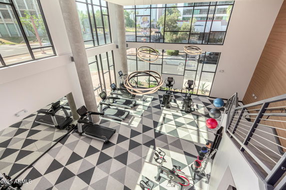Interior view of a modern gym with exercise machines and large windows.