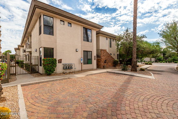 Front view of a multi-story building with balconies and a gated entrance.