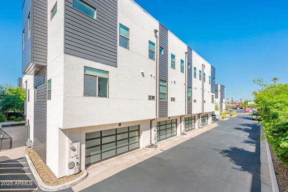Side view of a modern multi-story building with garage doors on the ground level.