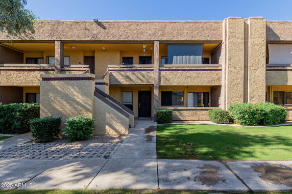 Front view of a two-story building with balconies and a staircase.