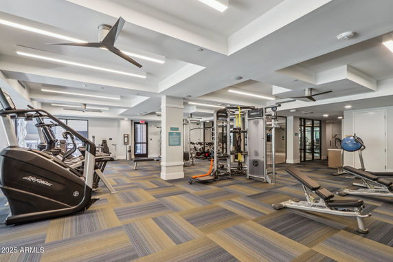 Interior view of a modern gym with exercise equipment and ceiling fans.