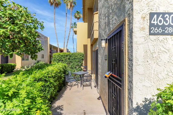 Front view of a residential building entrance with a small patio and outdoor seating.