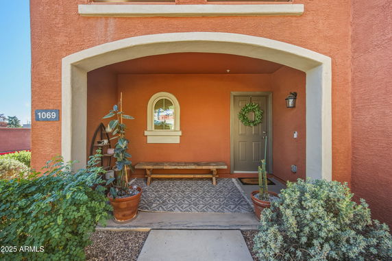 Front view of a house with an arched entryway and a gray door, marked with the number 1069.