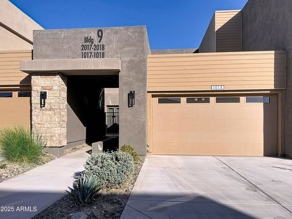 Front view of a modern building with a garage and entrance walkway.