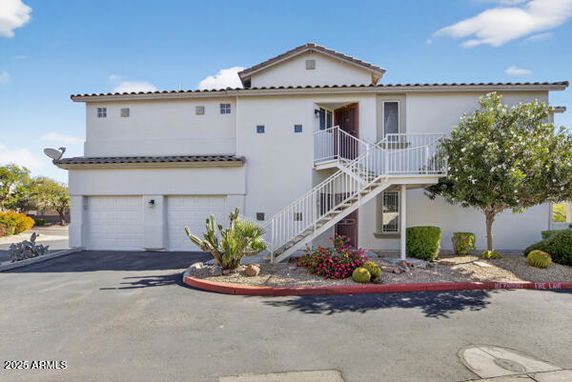 Front view of a two-story building with an external staircase and garage.