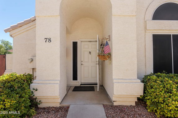 Front entry view of a house with an archway and a partially open door.