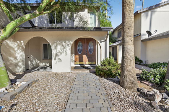 Front view of a two-story house with arched entryway and wooden double doors.