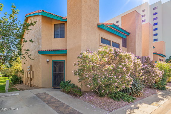 Front view of a two-story building with a stucco exterior, decorative window shutters, and a tiled roof.