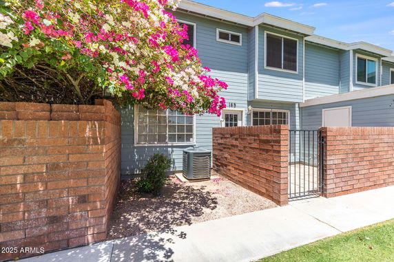 Front view of a two-story house with brick wall and gate.
