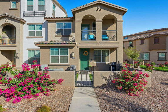 Front view of a two-story house with a balcony and arched entrance.