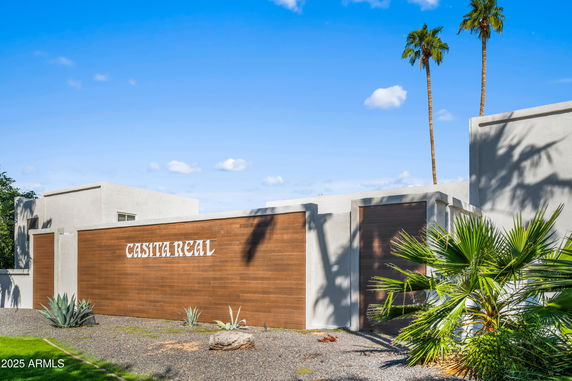 Front view of a modern building with a wooden accent wall and desert landscaping.