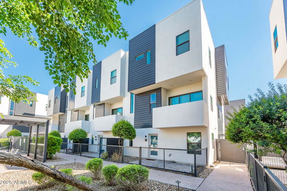 Front view of modern three-story townhouses with balconies and large windows.