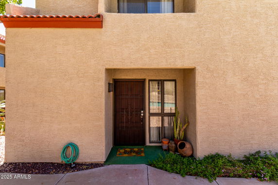 Front view of a house entrance with a metal door and adjacent window.