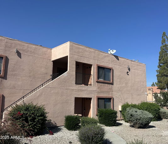 Front view of a two-story building with external staircases and satellite dishes on the roof.