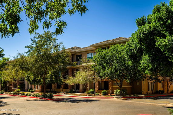 Front view of a three-story residential building with trees in front.
