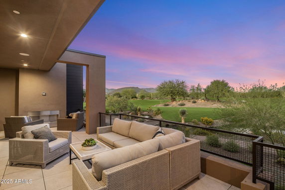 Outdoor seating area with a view of a golf course and sunset.