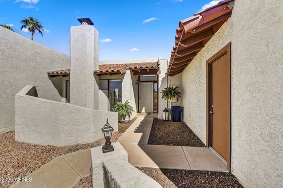 Front view of a house with a stucco exterior and clay tile roof.