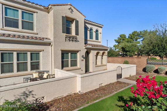 Front view of a two-story house with a walled patio and arched windows.