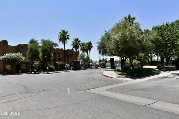 Front view of a residential building with gated entrance and palm trees.