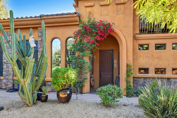 Front view of a house with an arched doorway and decorative plants.