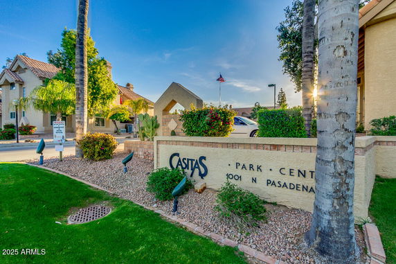 Front view of a residential building entrance with name sign and landscaping.