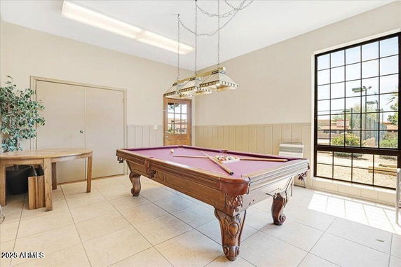 Room with a billiards table and large windows.