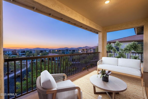 Balcony view over residential area with distant mountains at sunset.
