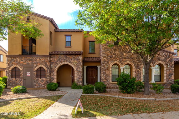 Front view of a two-story house with stone façade and arched windows.
