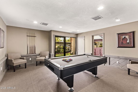 Room with a billiards table and two chairs.