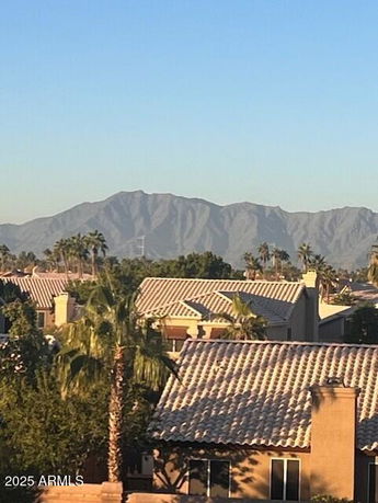 Panoramic view showing rooftops of residential buildings with mountains in the background.