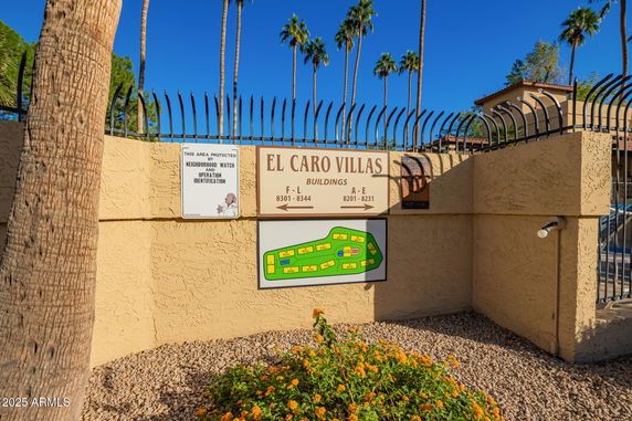 Elevated view of a villa entrance with signage and security wall.