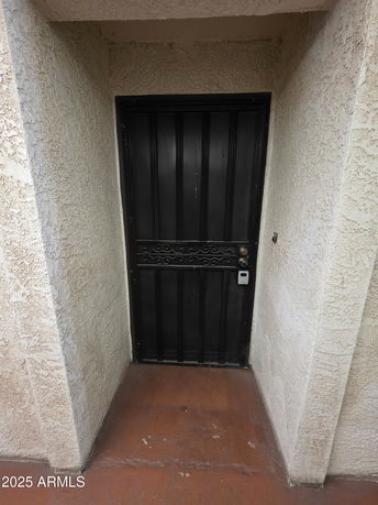 Front view of a building with a black metal door and textured walls.