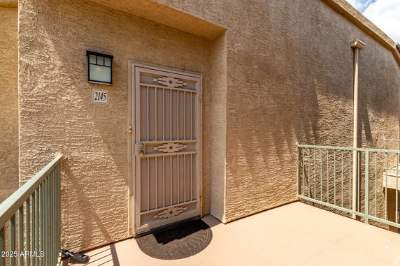 Front view of a building entrance with a metal door and wall-mounted light fixture.