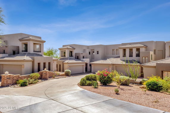 Front view of a modern multi-story house with attached garages and landscaped front yard.