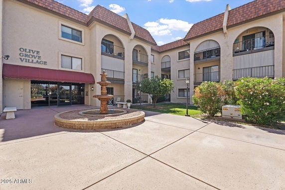 Front view of a multi-story apartment building with a central fountain.
