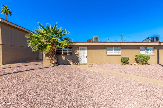 Front view of a single-story house with a flat roof and multiple windows.