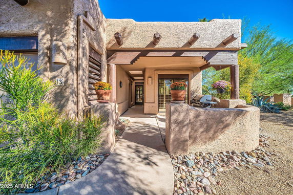 Front view of a house with stucco walls and decorative beams.