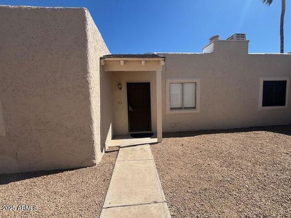 Front view of a single-story house with a simple entrance and gravel front yard.