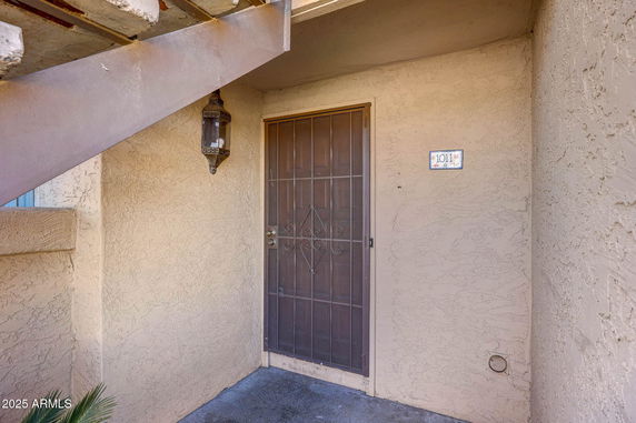 Entrance view of a building with a metal security door and a wall-mounted light fixture.