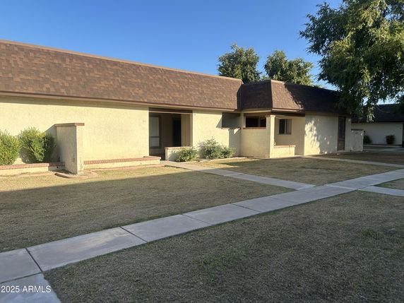 Front view of a single-story house with a brown roof and light-colored walls.