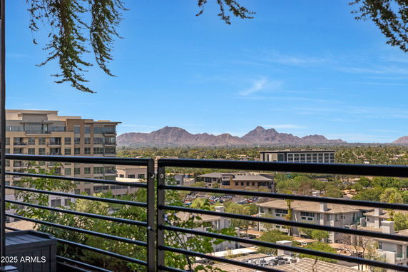 Panoramic view from a balcony overlooking buildings and distant mountains.