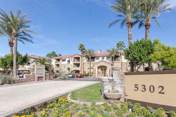 Front view of a multi-story residential building with palm trees and a driveway.