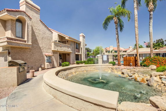Front view of a two-story house with stucco walls and a fountain in front.