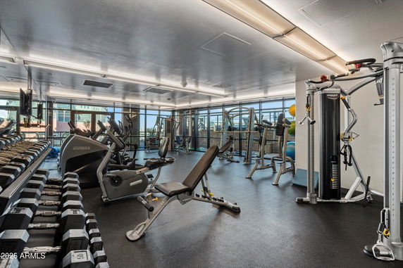 Indoor gym area with exercise equipment and large windows.