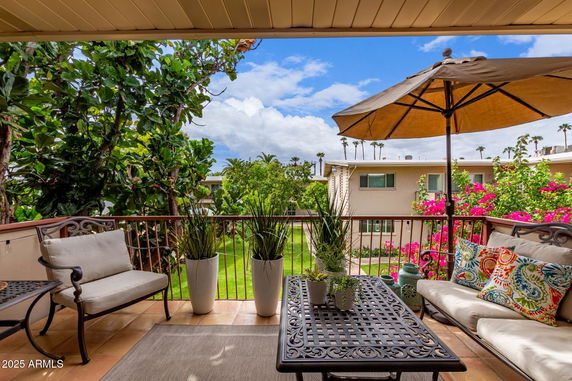 Patio view with outdoor furniture overlooking a garden and other buildings.