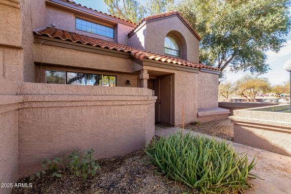 Front view of a house with a terracotta roof and textured walls.