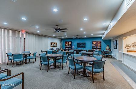 Room with tables and chairs arranged for recreation, blue walls, and bookshelves.