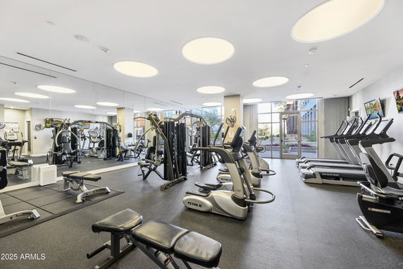 Interior view of a modern gym with fitness equipment and large mirrors.