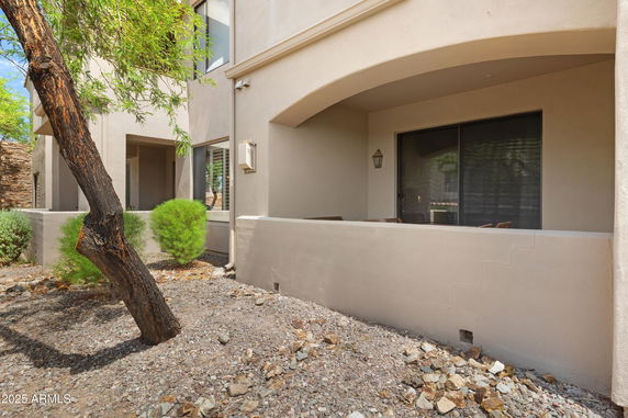 Front view of a house with an arched entryway and sliding glass door.